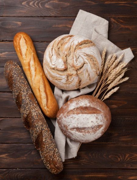 Various crusty bread and buns on wooden background. Top view